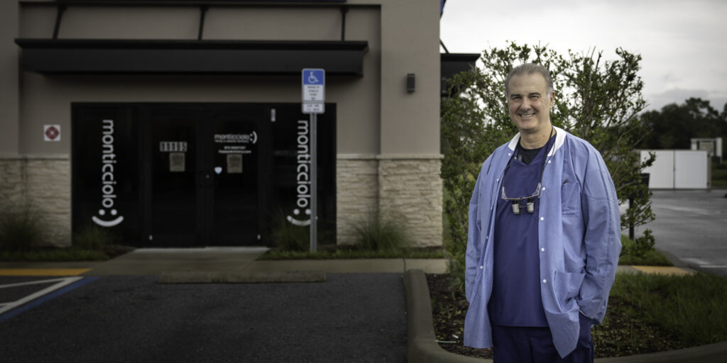 Smiling dentist outside Monticello dental office.
