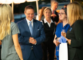 Man in suit talks to women at event.