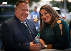 Couple smiles, holding drinks and water.