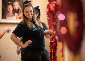 Smiling woman in "smile.it's" shirt.